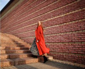 woman in black midi dress and long red coat