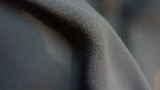 Close-up of Nida fabric showing detailed woven texture with soft folds and a muted gray tone