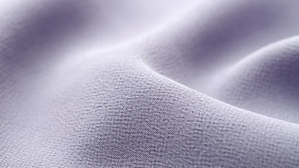 Close-up of soft lavender crepe fabric showing detailed texture and smooth, flowing folds.