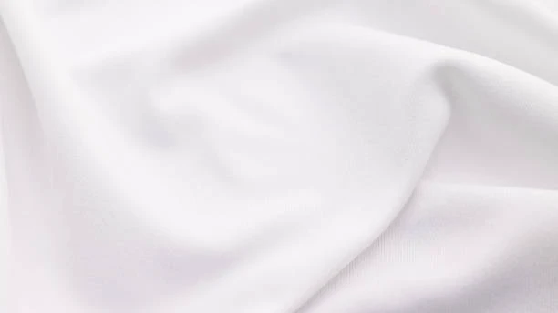 Close-up of soft white cotton fabric texture with gentle folds.